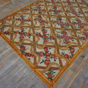 Low-pile rug in cream with red roses and a yellow ribbon trellis pattern on distressed gray wood floors.