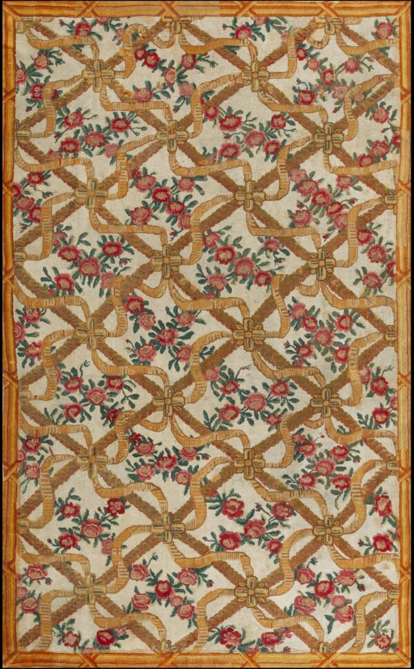 Cream rug patterned with red roses and a repeating lattice of gold and brown woven ribbons.