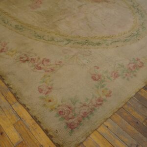 Shaggy beige rug with pink and green floral borders lies diagonally across worn wood flooring.