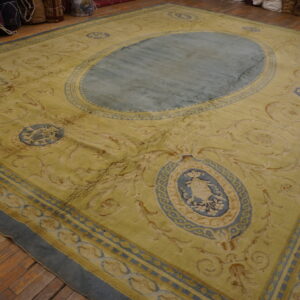 Yellow rug featuring blue cartouches and a central oval medallion on wide plank wood floors.