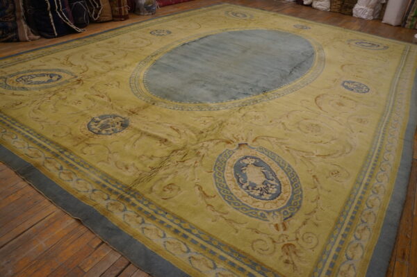Yellow rug featuring blue cartouches and a central oval medallion on wide plank wood floors.