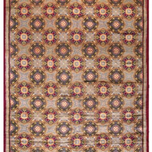 High-pile rug featuring repeating multicolored medallions on a dusty blue field with a wide, deep red border.