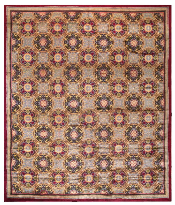 High-pile rug featuring repeating multicolored medallions on a dusty blue field with a wide, deep red border.