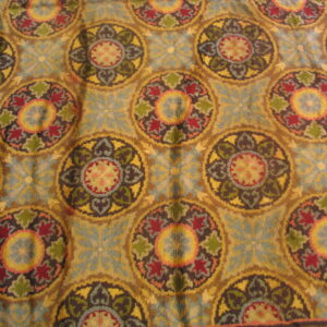 Repeating distressed medallion pattern rug in faded teal, gold, burgundy, and olive green colors.