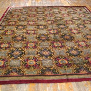 Multi-colored medallion rug with a maroon border resting on light brown distressed wood flooring.
