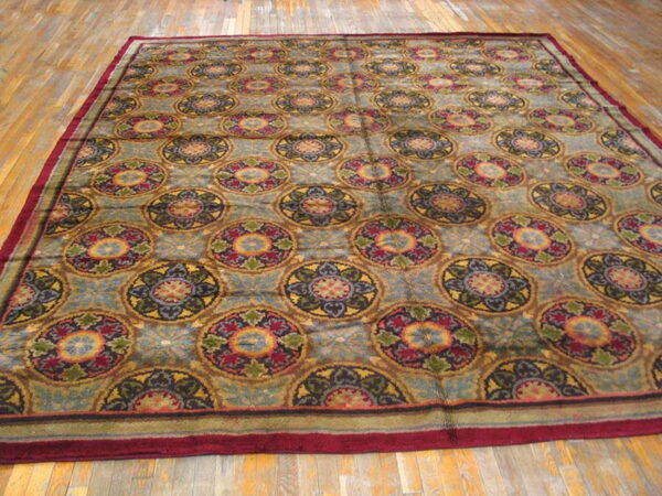 Multi-colored medallion rug with a maroon border resting on light brown distressed wood flooring.