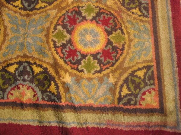 Close-up of a high-pile rug detail featuring ornate floral medallions in gold, red, dusty blue, and green.