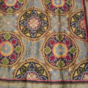 High-pile rug featuring repeating medallions in blue, red, gold, and green with a wide maroon border.