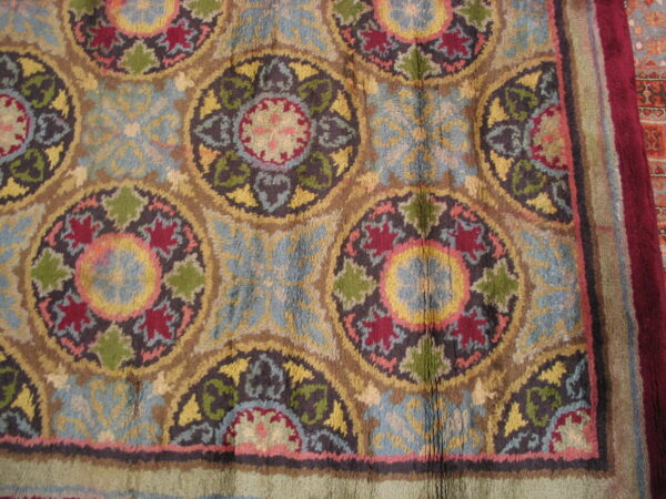 High-pile rug featuring repeating medallions in blue, red, gold, and green with a wide maroon border.