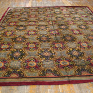 Large rug with repeating colorful medallions and a prominent red border on worn wooden floors.
