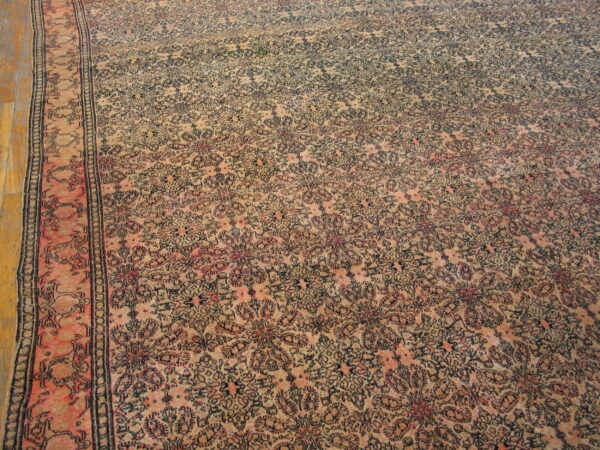 Low-pile rug with dense floral patterns in beige, dark blue, and pink on wood floor.
