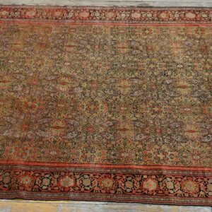 Ornate area rug in earthy tones of tan, red, and dark brown covers distressed wooden flooring.