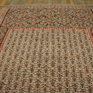 Traditional cream and rust-red patterned rug featuring detailed borders displayed on rustic wood planks.