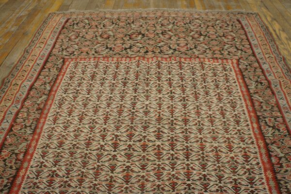 Traditional cream and rust-red patterned rug featuring detailed borders displayed on rustic wood planks.