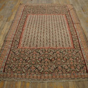 Low-profile rug featuring intricate red, black, and pale designs rests on distressed wooden planks.