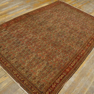 Rectangular rug with red and beige repeating pattern and complex borders on distressed wood planks.