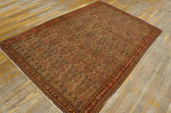 Rectangular rug with red and beige repeating pattern and complex borders on distressed wood planks.