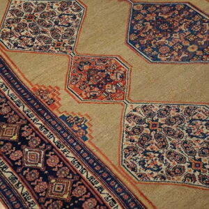 A tan rug field contrasts with repeating navy and red intricate octagonal medallions and a dark geometric border.