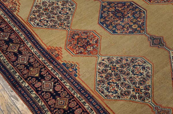 A tan rug field contrasts with repeating navy and red intricate octagonal medallions and a dark geometric border.