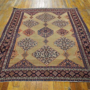 Tan rug with large, linked navy blue and red geometric medallions on a polished wood floor.