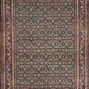 Dark, traditional rug densely patterned with ornate floral motifs in muted pink, teal, and beige.