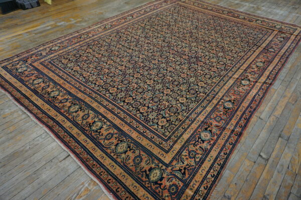 Low-pile area rug with a dense navy and rust traditional pattern displayed on weathered wood plank flooring.
