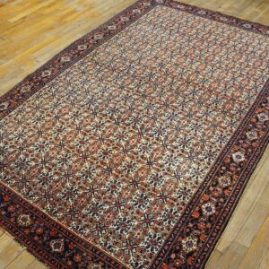 Low-pile rug featuring a dense red, cream, and navy repeating pattern on rustic wood flooring.