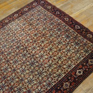 Cream, rust, and blue patterned rug with a wide dark border rests on rustic wood planks.