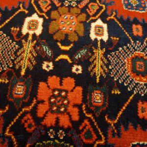 The dense pile rug displays stylized red and orange motifs against a rich navy background.