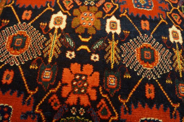 The dense pile rug displays stylized red and orange motifs against a rich navy background.