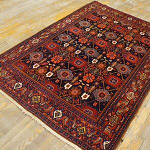 Navy and rust colored traditional rug with stylized motifs placed on pale, plank wood flooring.