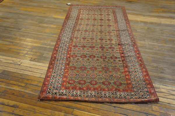 A long runner rug featuring tan, red, and blue geometric patterns rests on distressed wooden floors.