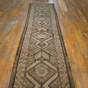 Geometric brown, tan, and cream runner rug displayed along distressed orange-toned hardwood flooring.