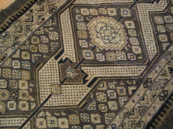 Detailed view of a brown and beige geometric rug pattern with blue and purple accents.