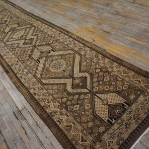 Geometric brown runner rug with tan accents on weathered wooden plank flooring.