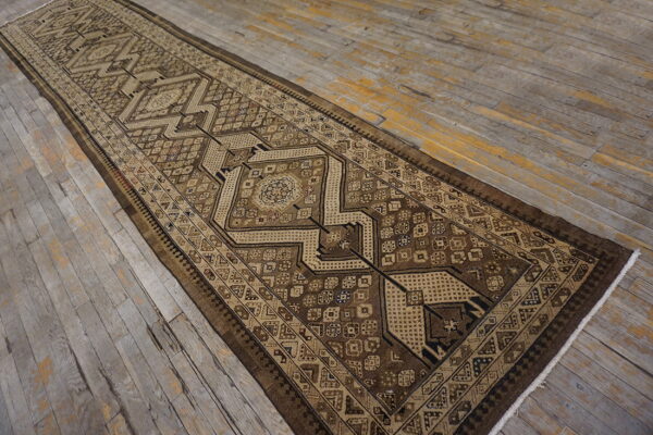 Geometric brown runner rug with tan accents on weathered wooden plank flooring.