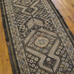 Long geometric runner rug in brown, beige, and blue with central medallions on light wood flooring.