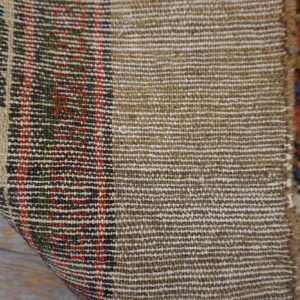 Detail showing the dense, tight tan weave of the rug's backing and its colorful patterned pile.