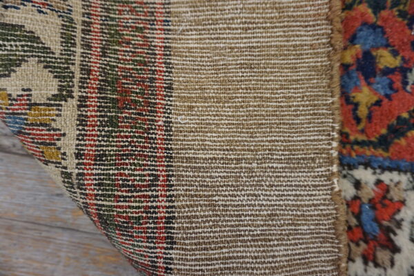 Detail showing the dense, tight tan weave of the rug's backing and its colorful patterned pile.