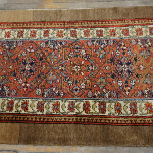 Rust floral runner rug with solid brown edges rests on light wood plank flooring.