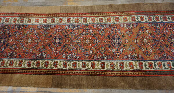 Rust floral runner rug with solid brown edges rests on light wood plank flooring.
