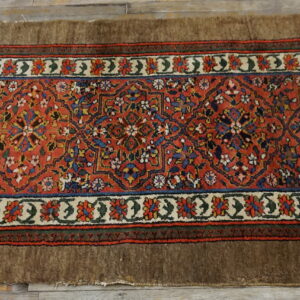 Red and blue patterned runner with wide brown edges resting on rustic gray wood planks.