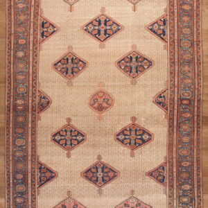 Elongated beige rug featuring repeating geometric diamond motifs in navy, rust, and muted pink borders.