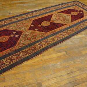 Geometric runner rug in deep blue, red, khaki, and gold rests on a distressed wood floor.