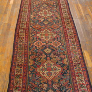 Geometric patterned runner rug with navy and red tones lies centered on light wooden flooring.