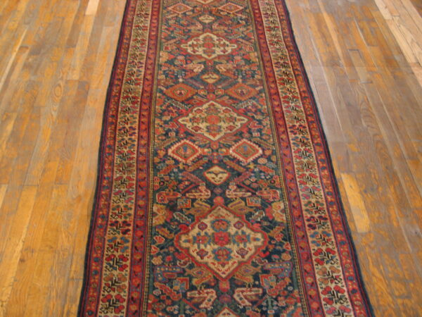 Geometric patterned runner rug with navy and red tones lies centered on light wooden flooring.