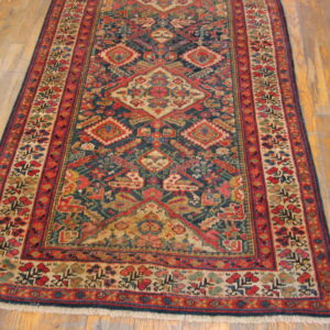 Geometric runner rug in deep blue, red, and tan tones laid upon light wood floorboards.