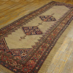 Tan runner with navy and red geometric medallions and wide borders rests on distressed wood flooring.