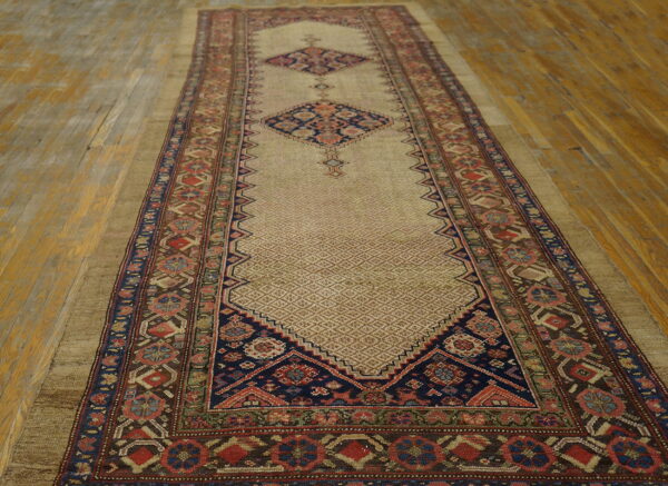 Geometric runner with a light brown diamond field, navy medallions, and multicolored borders on hardwood.