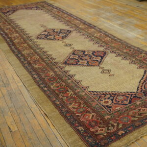 Low pile runner with a beige field, bold blue and red geometric medallions, resting on weathered wood.